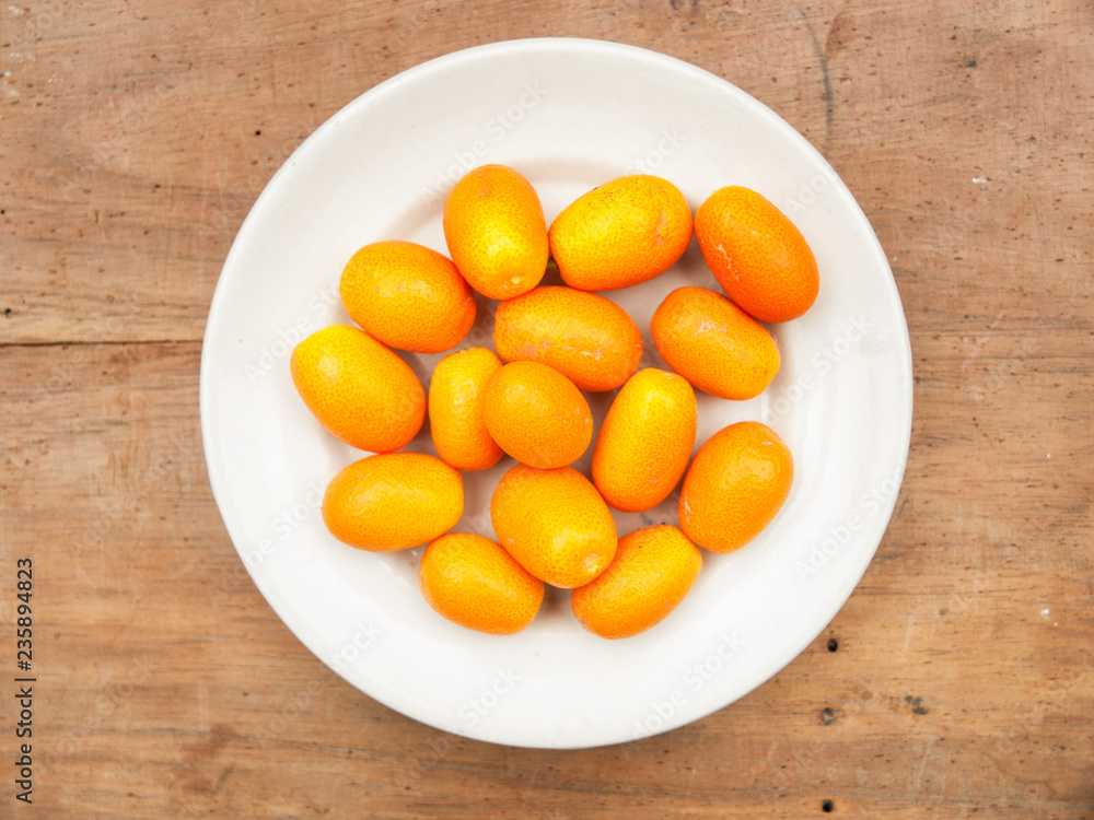 Quinotos kumquat en plato blanco sobre mesa de madera Quinotos kumquat en plato blanco sobre mesa de madera