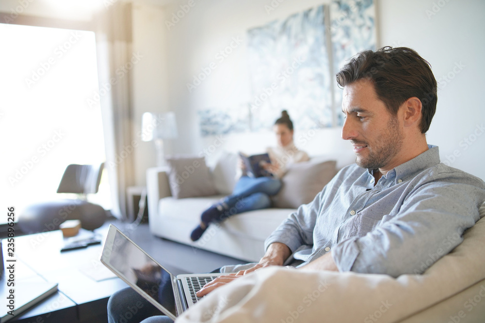  Handsome caucasian man with computer and wife in background