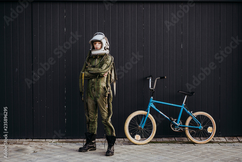 Stampa su tela Portrait of a boy on a bicycle in street astronaut dress