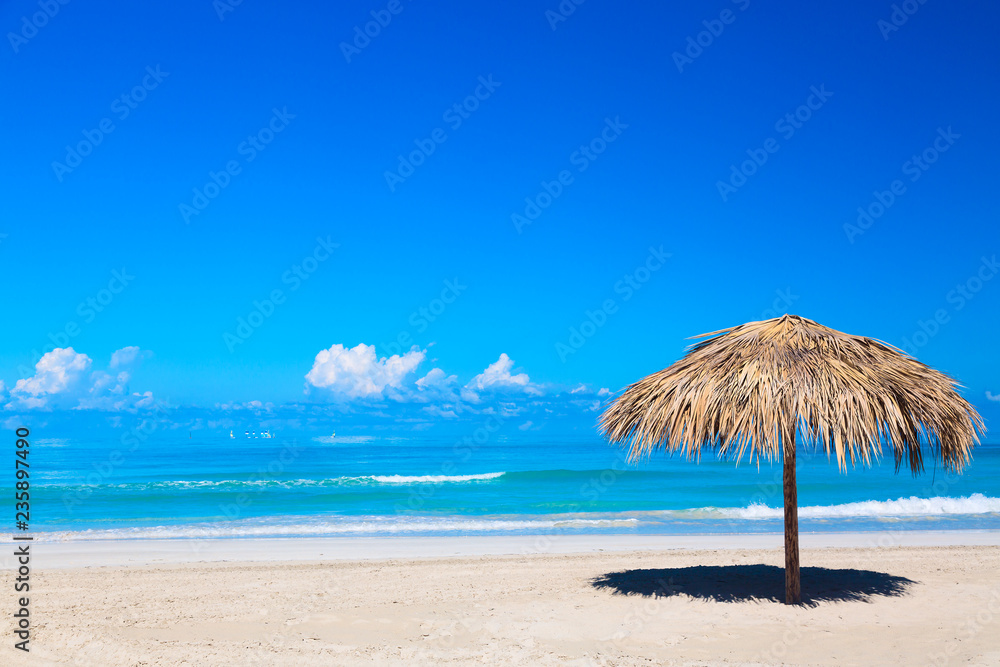 Straw umbrella on empty seaside beach in Varadero, Cuba. Relaxation, vacation idyllic background. Straw umbrella on empty seaside beach in Varadero, Cuba. Relaxation, vacation idyllic background.