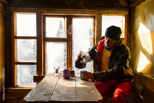 Traveler is drinking coffee and dreaming in a old mountain hut