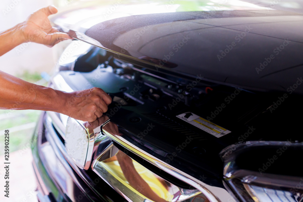 The man opened the hood of car and looking for a malfunction.