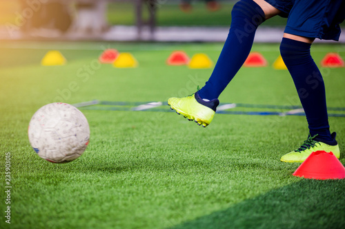 Soccer player jump and stomp for trap and control football with blurry marker cones and ladder drills.