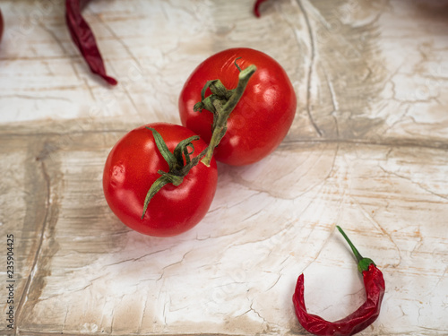 Two red pomir, hot pepper on a light wooden table photo