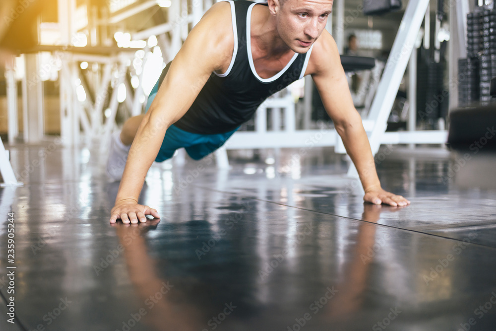 Strong man doing push up and exercises on floor at gym