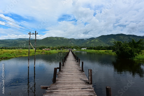 Bridge into nature. A wooden pier at Inle Lake surrounded by water leading toward the horizon. 