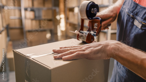 Warehouse Worker Checks and Sealing Cardboard Box Ready for Shipment.  photo