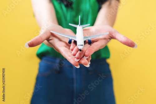 Young woman with toy airplane travel theme on a yellow background