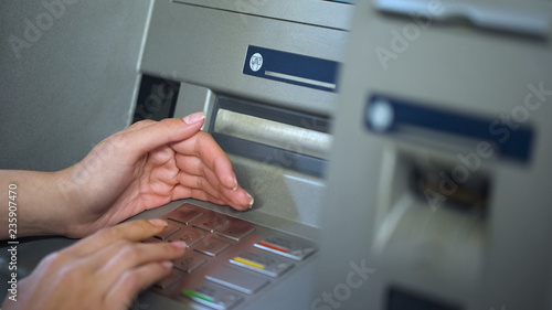 Φωτογραφία Lady hiding keyboard of automated teller machine while inserting her pin code