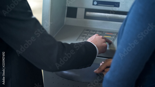 Female bank employee showing new client how to work with ATM, good service