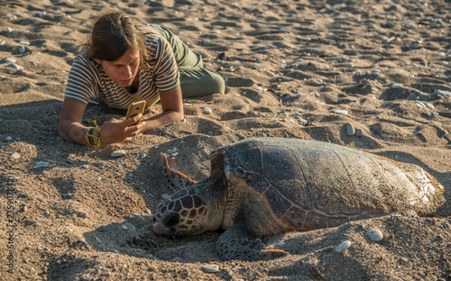 Girl making a photo of sea turtle
