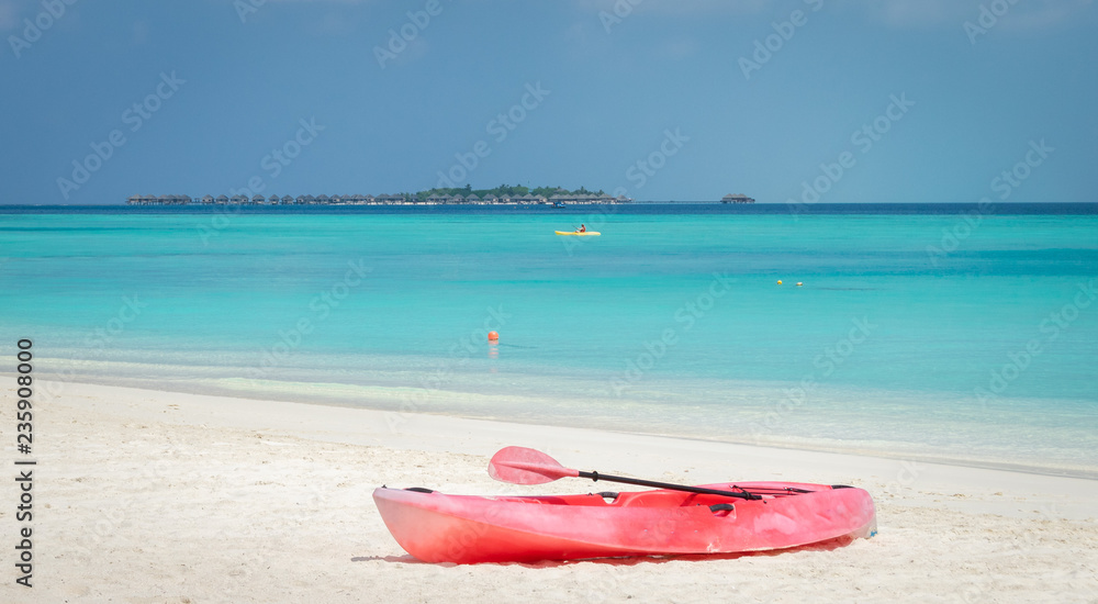 a red kayak on the white sand beach and the turquoise lagoon in Maldives a red kayak on the white sand beach and the turquoise lagoon in Maldives