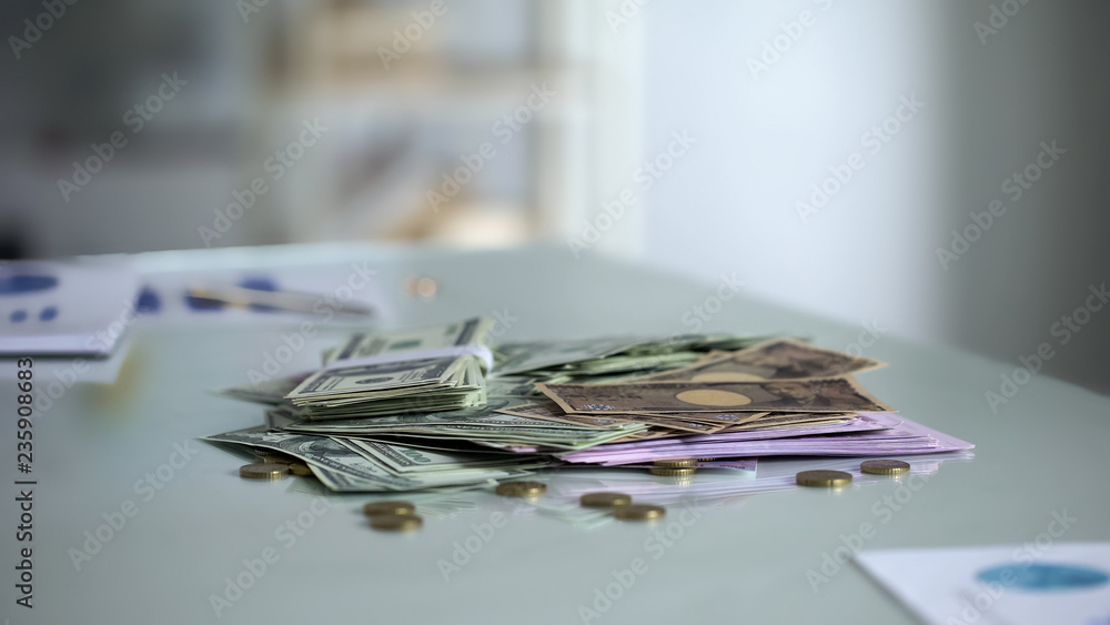 Pile of different currencies lying on table, savings or bank deposit, investment Pile of different currencies lying on table, savings or bank deposit, investment