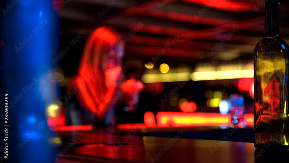 Pretty young female with glass drinking cocktail at bar, blurred background