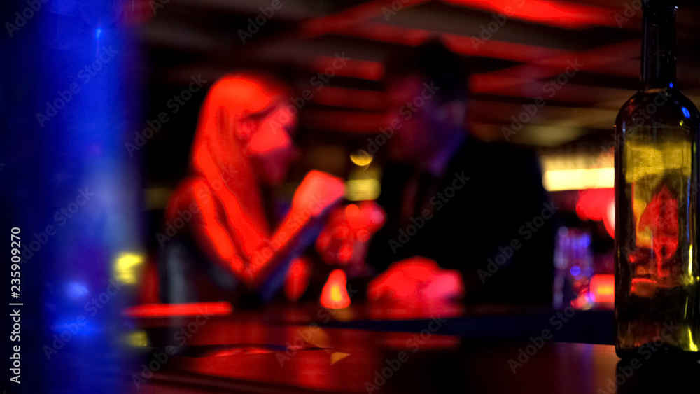 Man first meeting with lady in nightclub, talking privately, romantic atmosphere