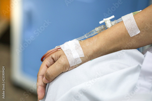 Close up hand woman patient with injection Saline in hand and during lying rehabilitation beds the hospital.