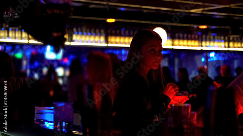 Attractive woman drinking cocktail at bar counter, enjoying music, nightlife