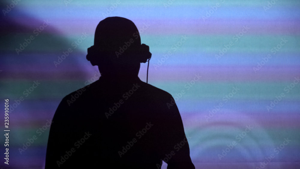 Man DJ silhouette on wall, performing for party, dancing to music, back view