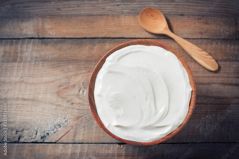 Greek yogurt in a wooden bowl on a rustic wooden table. Greek yogurt in a wooden bowl on a rustic wooden table.