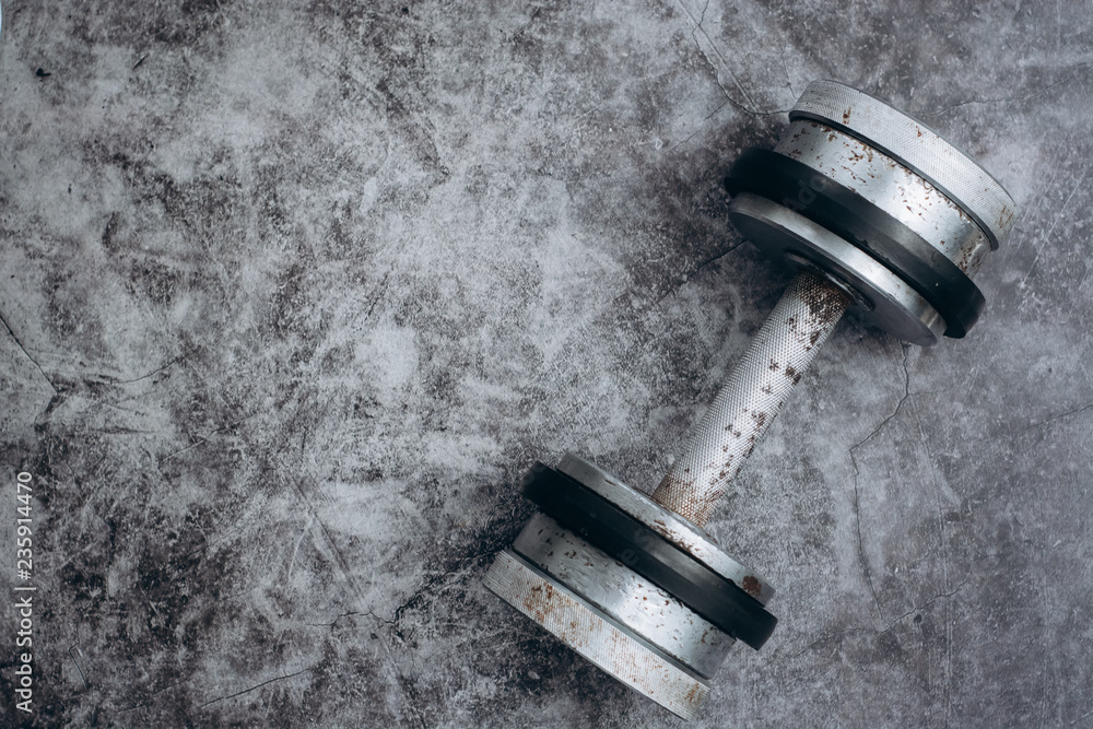 Fototapeta premium Fitness or bodybuilding concept background. Old iron dumbbells on grey, conrete floor in the gym. Top view. Healthz lifestyle.