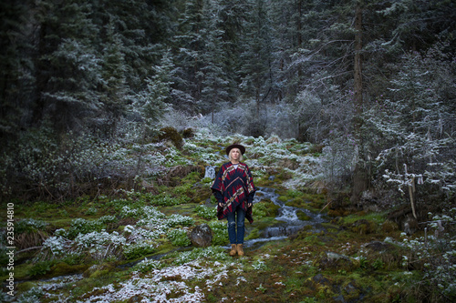 Stylish hipster girl in hat in autumn forest. Traveler woman exploring woods. Travel and adventure concept. Expedition vacation, space for text