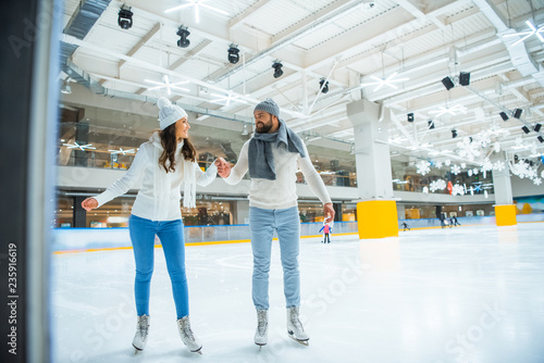 happy couple holding hands while skating on rink together