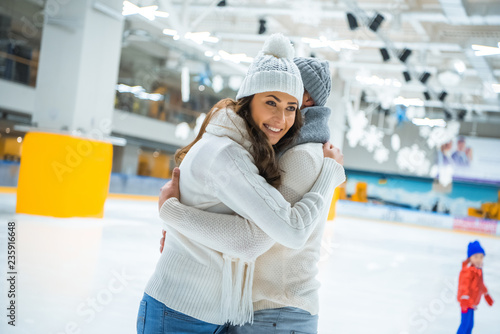 side view of couple in love hugging while skating on ice rink together