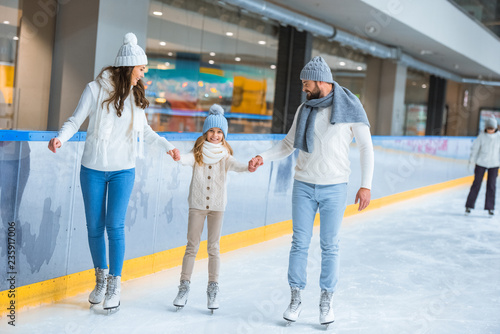 famiyl holding hands while skating on rink together