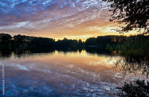 Sunset with reflecting trees on the horizon of the lake. Germany