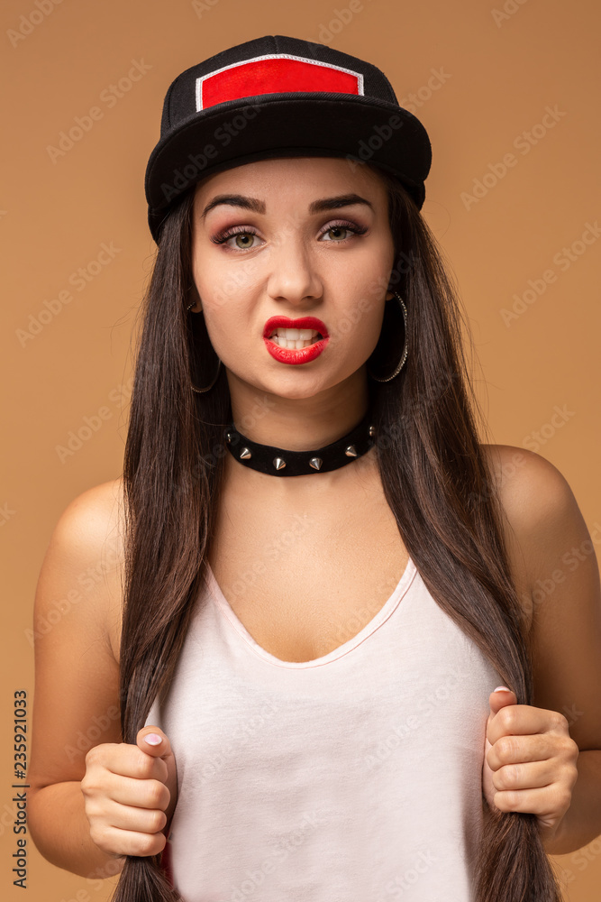 Close up positive portrait of pretty girl with amazing long brunette hair, bright sportive hat, bright make up, crazy funny face. Close up positive portrait of pretty girl with amazing long brunette hair, bright sportive hat, bright make up, crazy funny face.