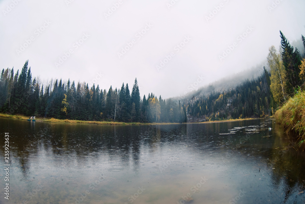 Fototapeta premium Autumn landscape: the river in fog among the wild forest and rocks.