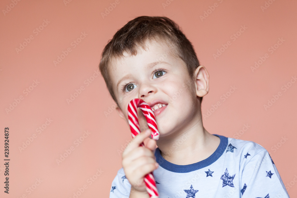 A cute boy eating candy sticks. Colored traditional handmade candy canes A cute boy eating candy sticks. Colored traditional handmade candy canes