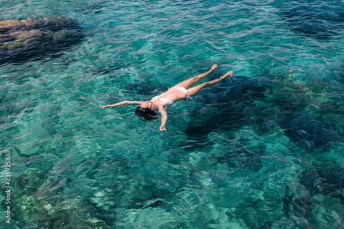 Top view of swimming woman in the transparent turquoise sea