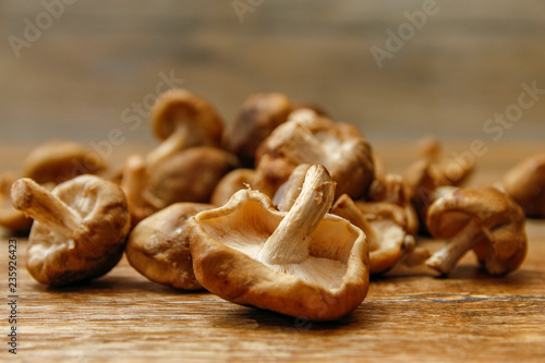 Fresh shiitake mushroom on wooden table, close-up photo in rustic ambient with low light