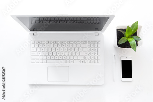completely white modern workspace with laptop, notepad, plant and pen photo