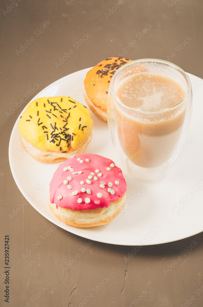 donuts in glazes and a glass of a cappuccino/donuts in glazes and a glass of a cappuccino on a white tray donuts in glazes and a glass of a cappuccino/donuts in glazes and a glass of a cappuccino on a white tray