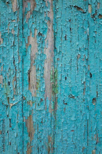 A close-up of an old weathered blue painted door with areas of flaking paint. Rustic textured background or flat lay concept.