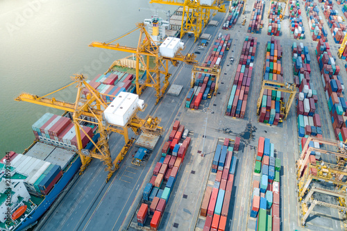 Logistics and transportation of container cargo freight ship with container crane in shipyard. Logistic import export business and transport industry. Aerial view taken from drone.