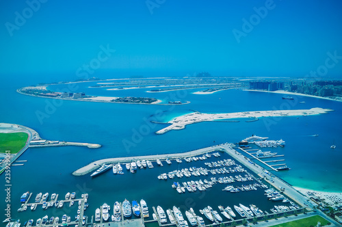 Aerial view of Palm Jumeirah Island with luxury yachts in the front. Development of Dubai.