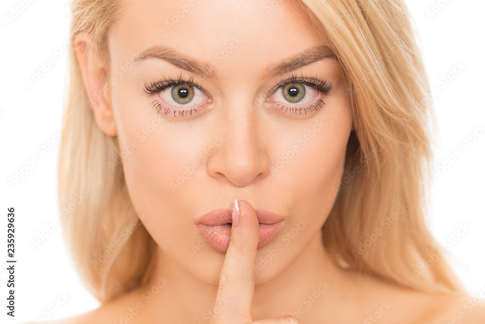 Close up portrait of a gorgeous young woman with perfect unblemished skin shushing to the camera with her fingers to her lips isolated secret quiet silence gesturing beauty cosmetology skincare spa Close up portrait of a gorgeous young woman with perfect unblemished skin shushing to the camera with her fingers to her lips isolated secret quiet silence gesturing beauty cosmetology skincare spa