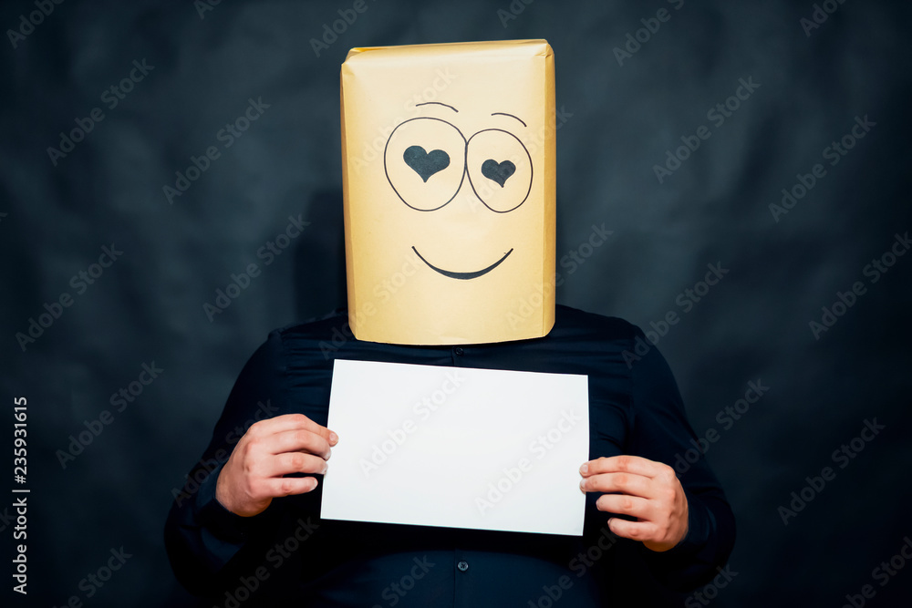 The concept of emotions. A man holds a blank white sheet in front of him. Looks lovers eyes. On the face smile and happiness. The concept of emotions. A man holds a blank white sheet in front of him. Looks lovers eyes. On the face smile and happiness.
