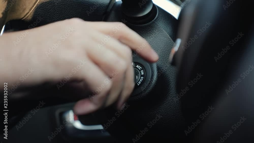 The man inside the car hand holds the key in the ignition, start the car engine The man inside the car hand holds the key in the ignition, start the car engine