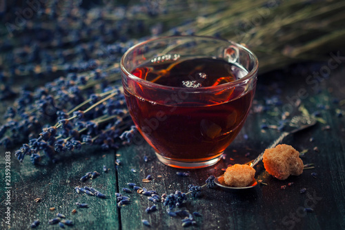 A cup of hot black tea with sugar and lavender on a dark wooden background. Breakfast concept.