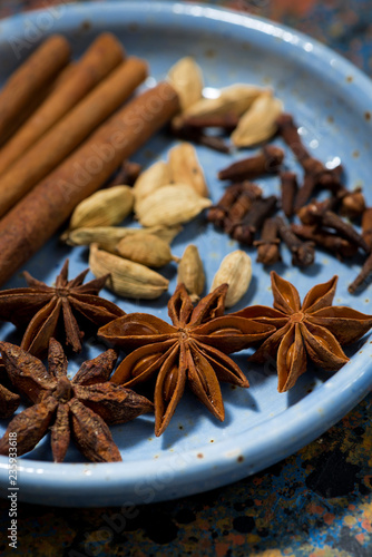 spices for masala tea in a blue plate, vertical
