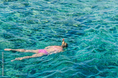 Woman swimming in blue sea. Snorkeling girl in full-face snorkeling mask. Coral reef in shallow sea. Snorkel undersea. Seashore underwater photo. Active seaside vacation. People and lifestyle concept
