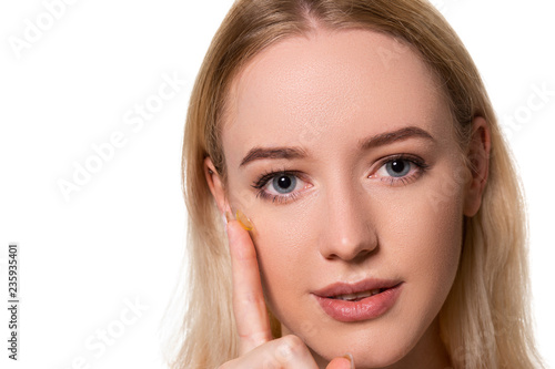 Young woman holding contact lens on index finger with copy space. Close up face of healthy beautiful woman about to wear contact lens.