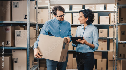 Obraz na plátně Female Inventory Manager Shows Digital Tablet Information to a Worker Holding Cardboard Box, They Talk and Do Work