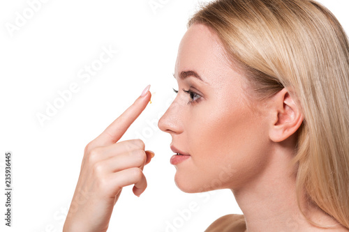 Young woman holding contact lens on index finger with copy space. Close up face of healthy beautiful woman about to wear contact lens.