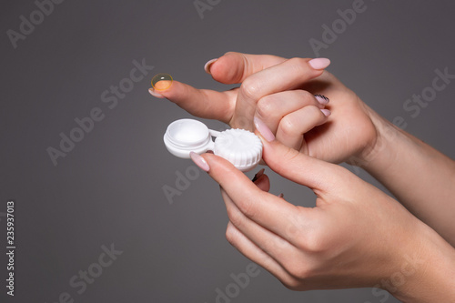 Contact eye lens. Close-up of woman hands holding white eye lense container. Woman fingers holding eye lense box.
