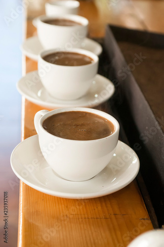 row of white cups with coffee with